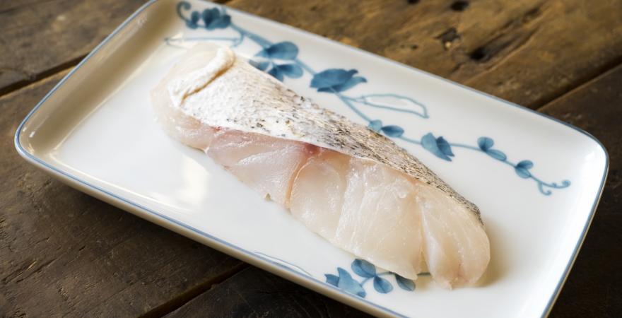 A piece of cod fish sitting on a Japanese design plate