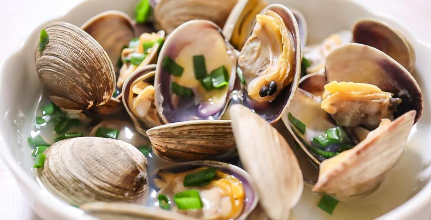 Steamed clams in a white bowl.