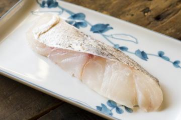 A piece of cod fish sitting on a Japanese design plate