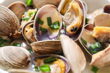 Steamed clams in a white bowl.